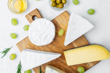 Üzüm ve zeytinlerle ahşap bir tahtaya dizilmiş lezzetli peynir çeşitleri..