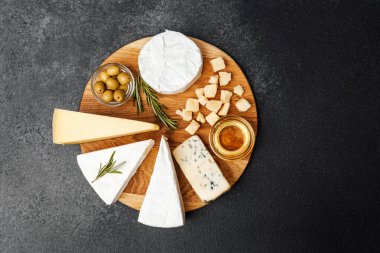 Tahtada çeşitli peynirler, zeytinler ve bal bulunur. Paylaşım için mükemmeldir..