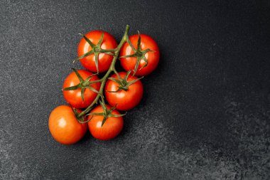 Olgun vişneli domates kümesi koyu bir tezgahta oturur, yemek için mükemmeldir..