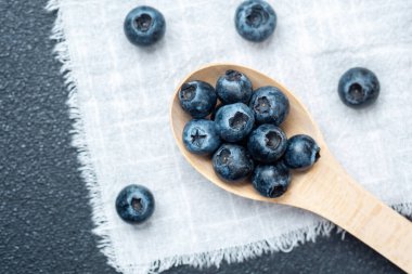 Sulu yaban mersinleri ahşap bir kaşık üzerinde sade bir kumaş yüzeyi üzerine dizilmiş..