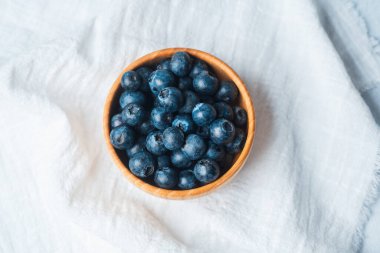 Taze yaban mersiniyle dolu bir kase, hafif, desenli bir kumaş üzerinde dinleniyor..