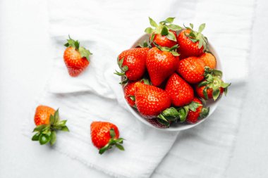 Olgun çilekler yumuşak keten kumaş üzerinde bir kasede güzelce sergilenir..