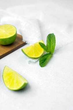Dilimlenmiş kireç ve nane yaprakları parlak bir yüzeye yerleştirilmiştir..