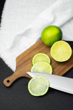 Misket limonları tahtanın üzerinde dilimlenmiş, yanında da bir kireç ve bıçak var..