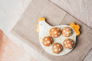 Beyaz papatya çiçekli Paskalya yumurtaları seramik tavuk tepsisinde.