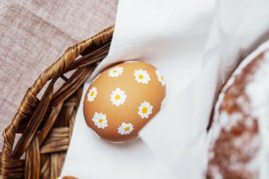 Kırsal sepetteki peçetede papatya desenli tek bir Paskalya yumurtası. El yapımı bahar tatili dekorasyonu.
