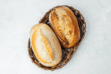 İki zanaatkar ekmek, hafif bir yüzeyde bir sepette dinleniyor..