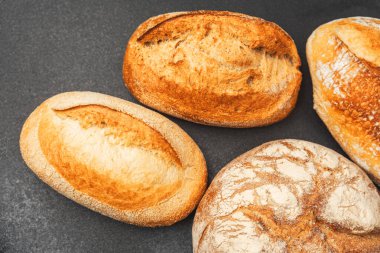 Koyu bir yüzeyde dört çeşit zanaatkar ekmek sergilenir, taze pişmiş gibi görünür..