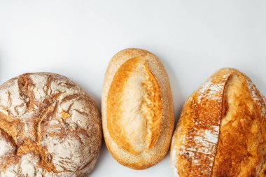 Farklı türde zanaatkar ekmeği temiz beyaz bir yüzey üzerinde düzgün bir şekilde düzenlenir..