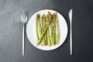 Taze ızgara kuşkonmaz, beyaz bir tabakta, çatal bıçakla düzgünce dizilmiş..