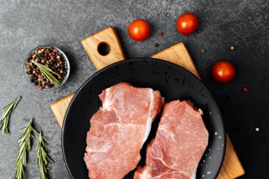 Sulu et taze baharat ve sebzelerle çevrili siyah bir tabakta dinleniyor..