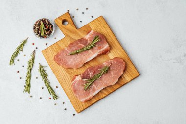 Biberiye ve baharatlarla ahşap bir kesme tahtasına iki domuz pirzolası konur..