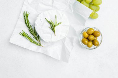 Hafif bir arka planda üzüm ve zeytinlerle süslenmiş taze peynir..