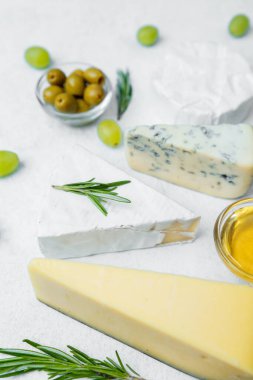 Çeşitli peynir türleri zeytin, üzüm ve bal ile dekoratif bir ortamda sıralanmış.