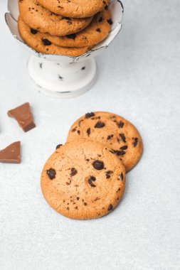 Çikolata parçacıklı kurabiyeler tezgahın üzerinde. Yanında da çikolata parçaları var..