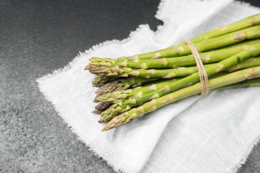 Parlak yeşil kuşkonmaz mızrakları beyaz keten kumaş üzerinde birbirine bağlanmış..