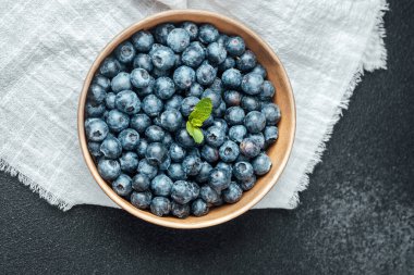 Taze yaban mersiniyle dolu bir kase dokulu siyah bir yüzeye oturur..