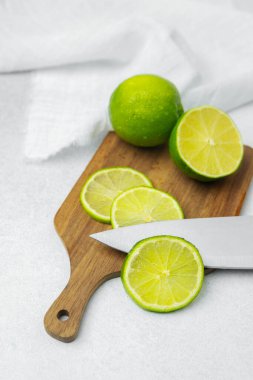 Taze limonlar kesme tahtasının üzerinde otururken biri bıçakla doğranır..