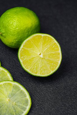 Dilimlenmiş ve bütün limonlar güzel bir şekilde koyu bir taş yüzeyde dizilmiş..