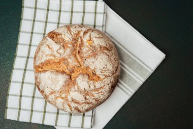 Taze pişmiş ekşi ekmek, mutfaktaki kareli bir havluya konur..