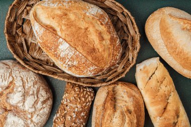 Bir dizi farklı ekmek türü koyu arkaplanda bir sepette görüntülenir.