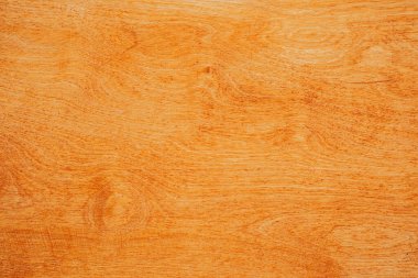 Sıcak turuncu renk ve karışık tahıl çizgilerinin yer aldığı ahşap bir yüzey..