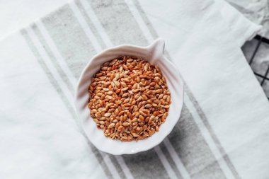 Keten tohumları bembeyaz bir kaseye yerleştirilir ve bez bir havluya yerleştirilir..