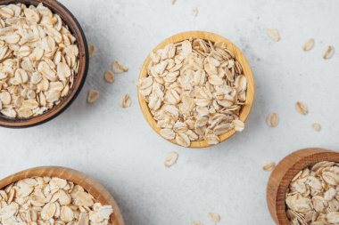 Hafif bir zemin üzerinde yulafla dolu çeşitli kaseler ve dağınık gevrek tanecikler..