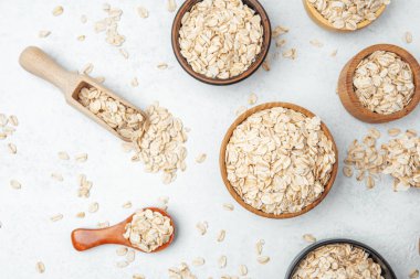 Yuvarlanmış yulaflı farklı kaseler hafif bir yüzeye yerleştirilmiş ve kepçeler etrafa saçılmıştır..