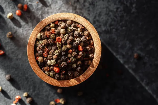 Ahşap bir kase biber güneş ışığıyla aydınlatılır..