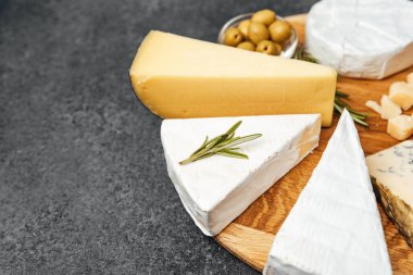 Güzel bir peynir çeşidi, zeytinli ahşap servis tahtasına dizilir..