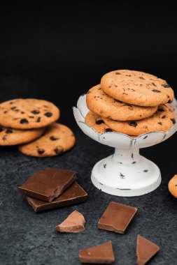 Çikolata parçalı kurabiyeler kırık çikolata karelerinin yanında duruyor..