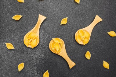 Çeşitli makarna şekilleri karanlık bir yüzeyde sanatsal olarak sergileniyor, yaratıcılığı gösteriyor..