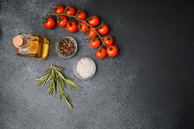 Kiraz domatesli, zeytinyağlı, biberiyeli ve tuzlu biberli yemek malzemelerinin en üst görüntüsü.