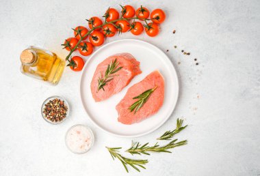 Baharat ve sebzelerle çevrili, beyaz tabakta biberiyeli iki dana biftek.