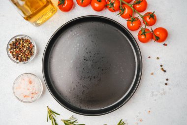 Domates, biberiye, tuz, yağ ve biber içeren yemek malzemelerinin olduğu boş siyah tabağın üst görüntüsü