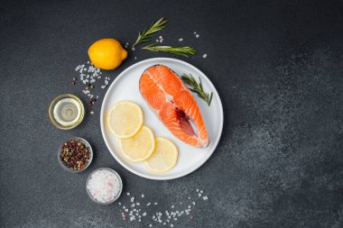 Canlı bir somon filetosu bir tabakta limon dilimleri ve otlarla süslenir..