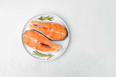 Biberiyeyle süslenmiş beyaz bir tabakta canlı somon kesikleri..