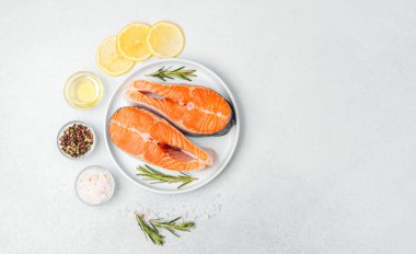 Taze somon biftekleri limon dilimleri ve pişirmeye hazır otlarla sergilenir..