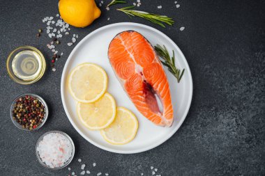 Limon dilimleri, tuz ve çeşitli baharatlarla bir tabağa konmuş somon filetosu..