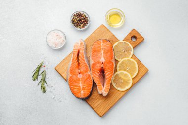 Limon dilimleri ve baharatla ahşap bir yüzeye dizilmiş somon filetoları..
