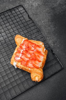 Altın hamurlu sıcak bir pasta dilimlenmiş taze çileklerle kaplıdır..