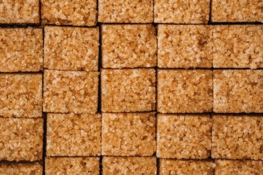 Kahverengi şeker küpleri, kırsal bir yüzeyde, pişirmeye hazır bir şekilde mükemmel bir şekilde dizilmiştir..