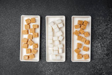 Değişik tipte şeker küpleri, arka planda üç tepsiye düzgünce yerleştirilir..