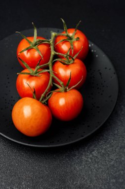 Siyah bir tabakta altı canlı domates tazeliklerini ve renklerini sergiliyor..