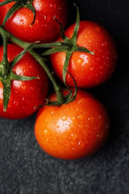 Siyah arka planda duran su damlacıkları olan parlak kırmızı domatesler..