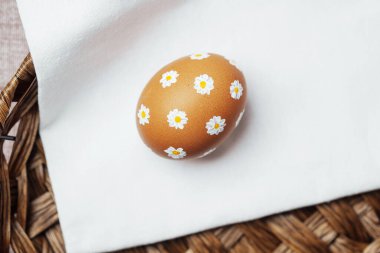 Kırsal sepetteki peçetede papatya desenli tek bir Paskalya yumurtası. El yapımı bahar tatili dekorasyonu.