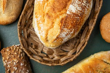 Düz bir yüzeyde kırsal bir sepette sergilenen kabuklu ekmek çeşitleri.