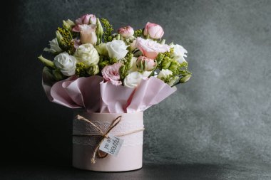 Dekoratif bir kutuda yumuşak pembe ve beyaz çiçekler bulunan güzel bir buket..