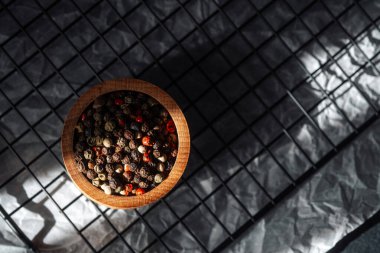 Ahşap bir kase buruşmuş kağıtta renkli biberler barındırır..